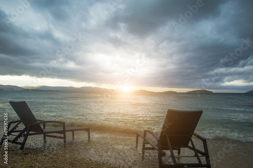 two sun loungers against sea and clouds