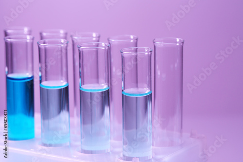 Test-tubes with blue liquid on purple background