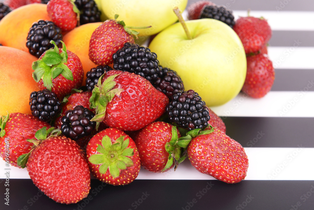 Fototapeta premium Ripe fruits and berries on striped background