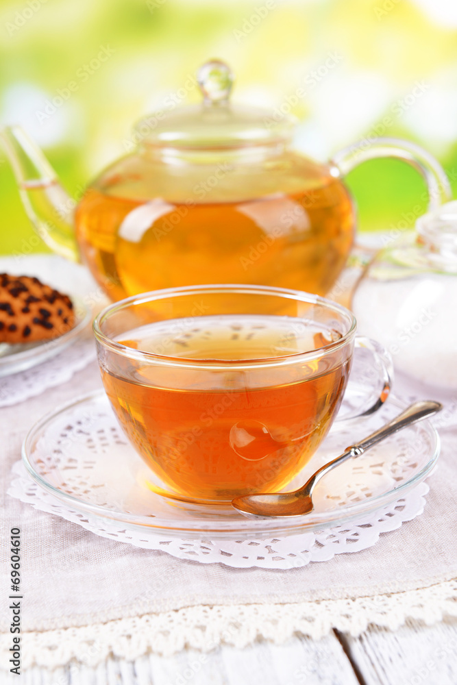 Teapot and cup of tea on table on bright background Teapot and cup of tea on table on bright background