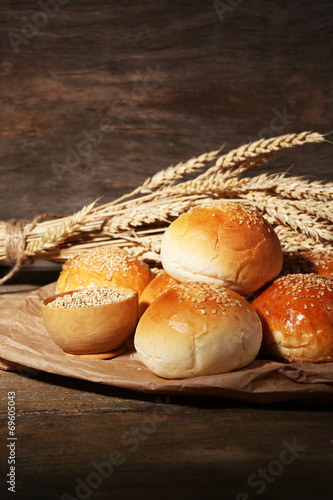 Tasty buns with sesame on wooden background
