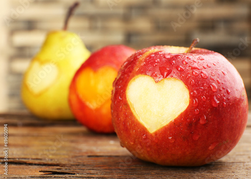 Ripe fruits with heart on wooden table, close-up photo