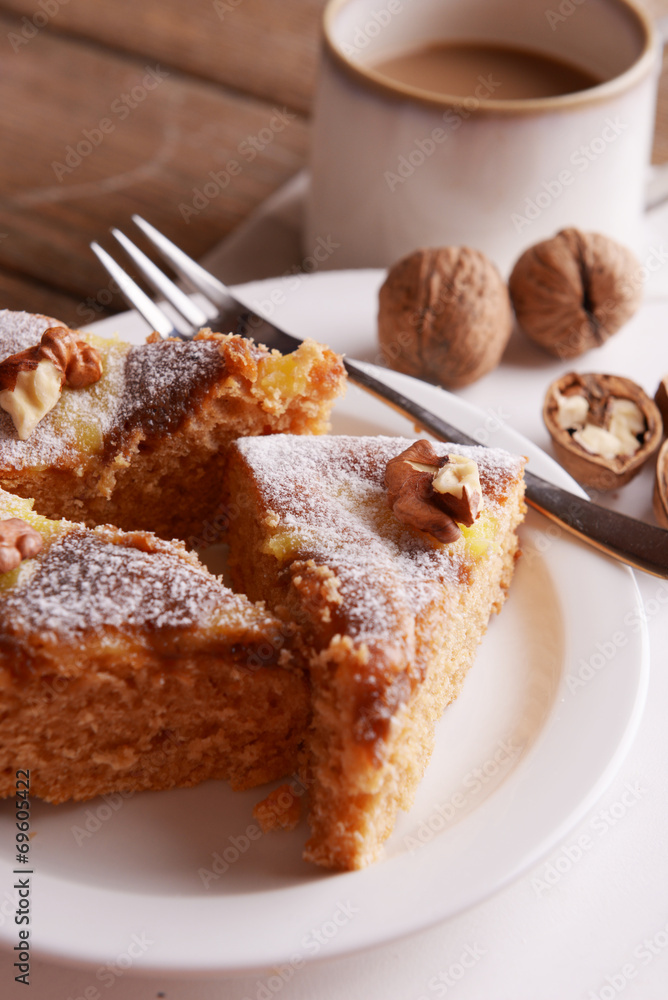 Pieces of delicious cake with nuts on plate on wooden table