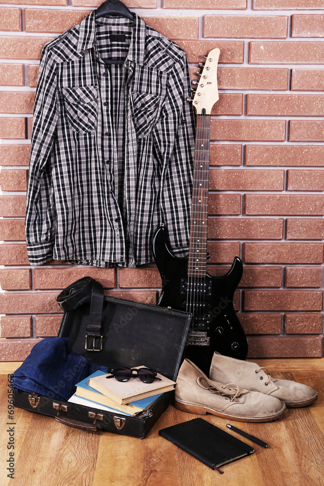 Guitar, clothes, boots and suitcase with books