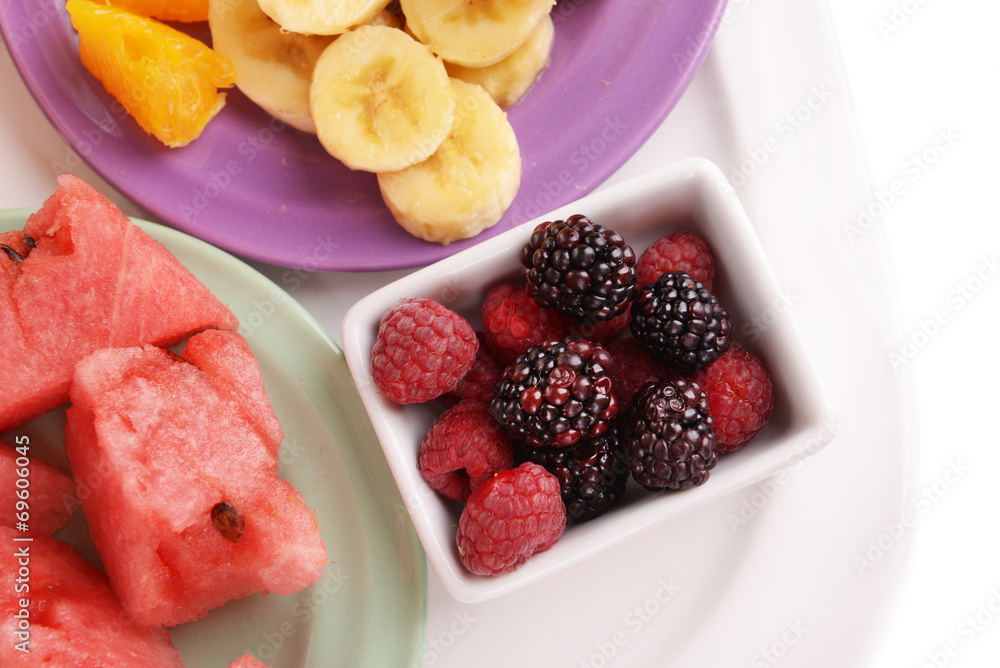 Slices of fruits with berries on plate close up Slices of fruits with berries on plate close up