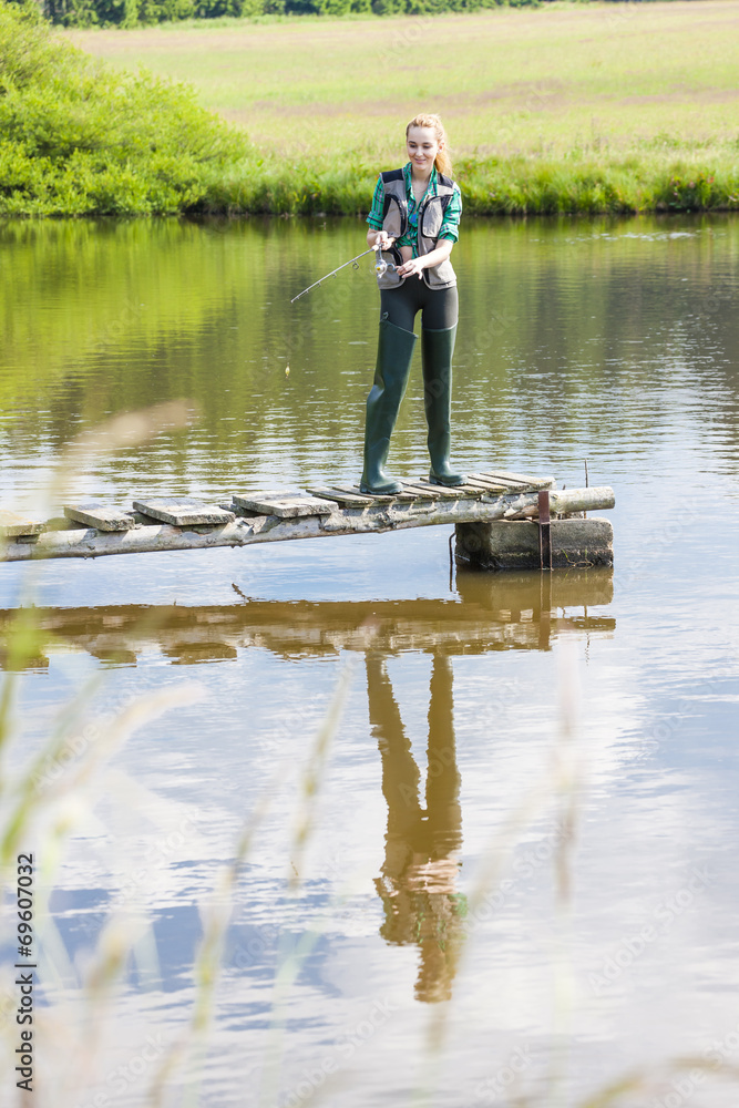 young woman fishing on pier at pond young woman fishing on pier at pond