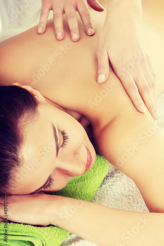 Beautiful woman lying on bed in spa salon.