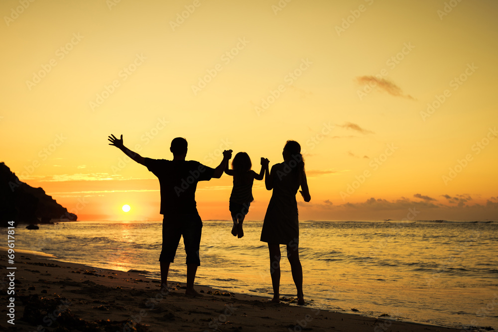 Fototapeta premium Szczęśliwa rodzina gra na plaży w czasie świtu