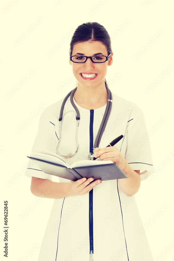Young female doctor wirting in a book. Young female doctor wirting in a book.