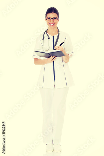 Young female doctor wirting in a book. photo