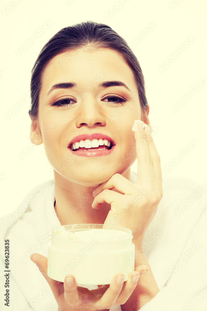Beautiful woman in bathrobe with face cream. Beautiful woman in bathrobe with face cream.