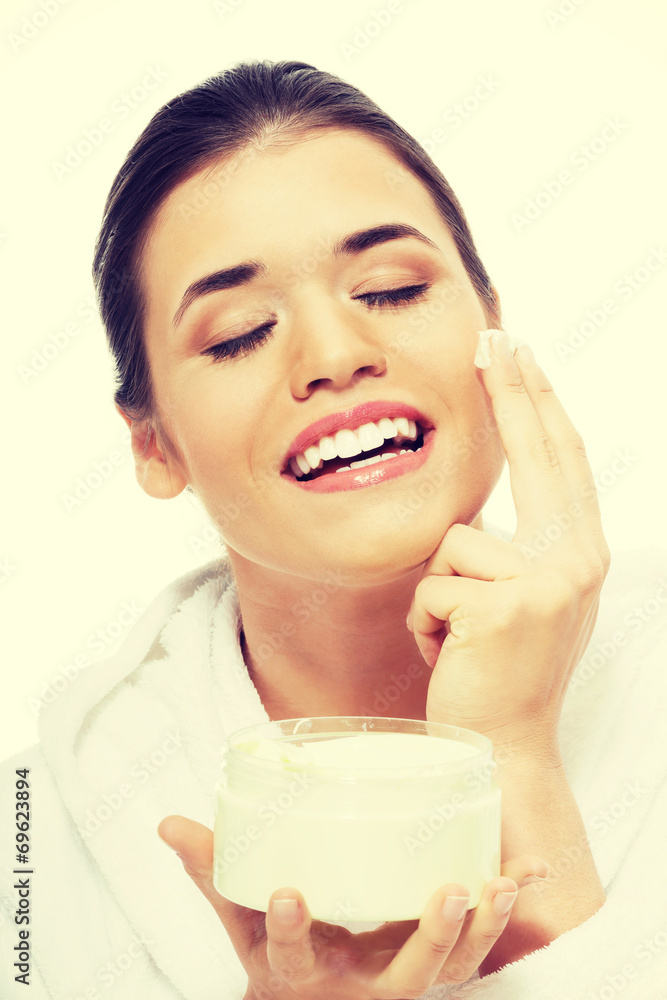 Beautiful woman in bathrobe with face cream. Beautiful woman in bathrobe with face cream.