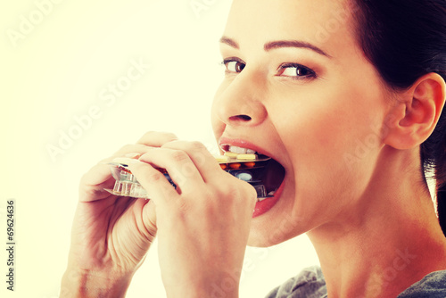 Casual beautiful woman trying to eat blister of pills.