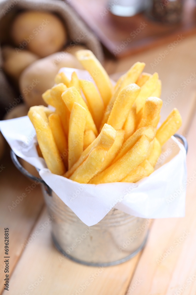 French fries in metal cup on wood table French fries in metal cup on wood table