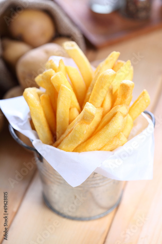French fries in metal cup on wood table