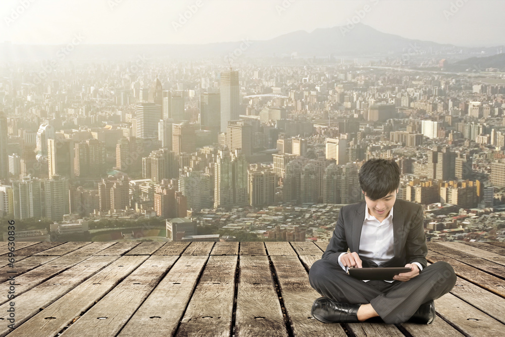 Asian business man using pad and sit on ground