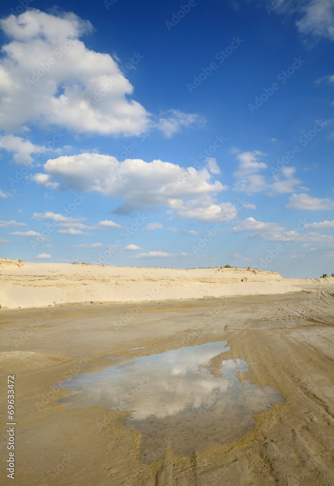 Sand quarry, heap of sand and puddle, beautiful landscape