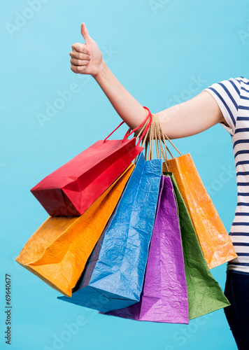 Woman holding shopping bags and showing thumb up