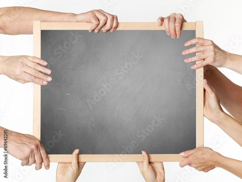 Many hands holding a blank blackboard