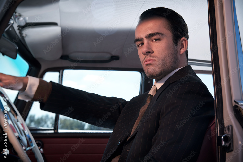Retro 60s fashion business man wearing grey suit with tie sittin Retro 60s fashion business man wearing grey suit with tie sittin