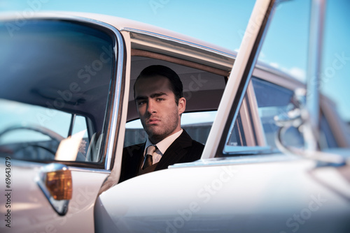 Fotografie Retro 60s fashion business man wearing grey suit with tie sittin