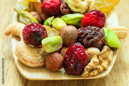 Varieties of dried fruits and nuts on wooden spoon.