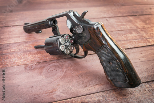black revolver gun with bullets isolated on wooden background