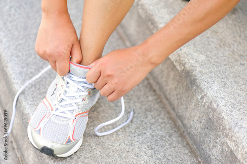 woman runner tying shoelace on stone stairs