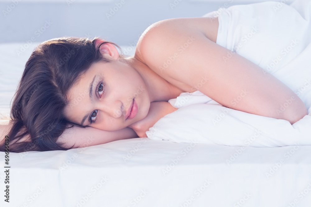 Beautiful brunette lying on bed smiling at camera Beautiful brunette lying on bed smiling at camera