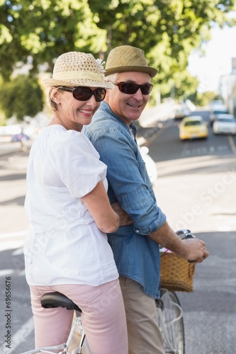 Happy mature couple going for a bike ride in the city