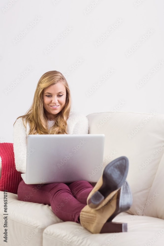 Pretty blonde relaxing on sofa with laptop