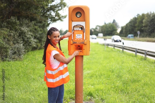 junge Frau an einer Notrufsäule