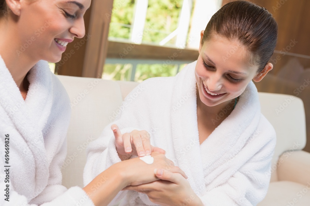 Woman applying cream to friend's hand Woman applying cream to friend's hand