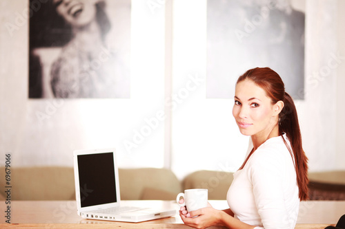 Frau mit Kaffeetasse am Laptop