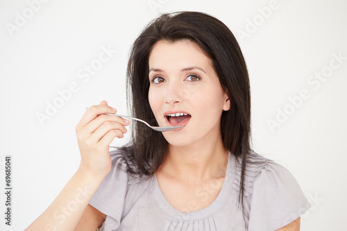 Studio Shot Of Woman Eating With Spoon On White Background