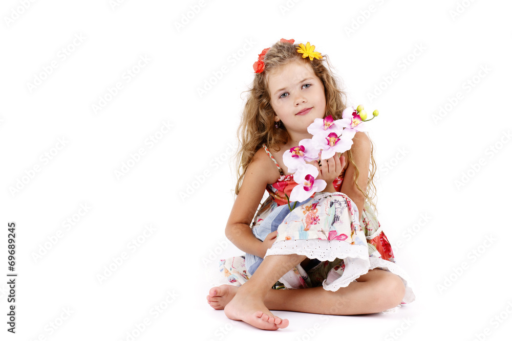Beautiful little girl sitting on the floor and holding orchid