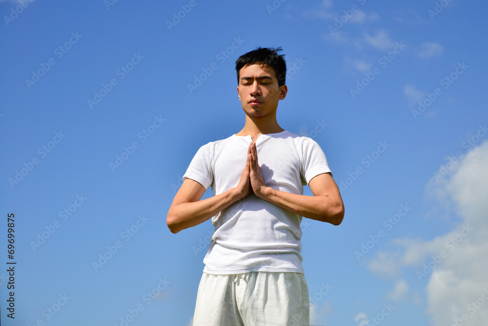 handsome man yoga routine against a blue sky
