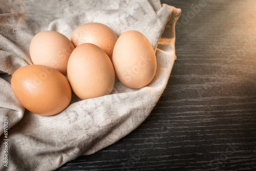 Chicken brown eggs in sackcloth on wooden background