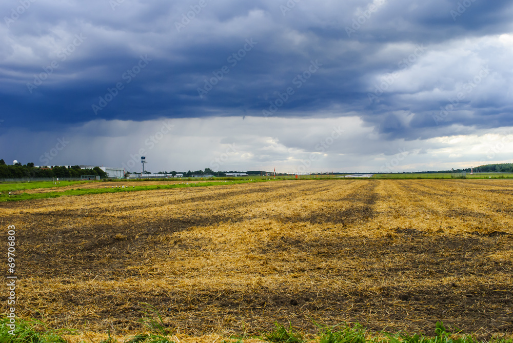 Fototapeta premium Dramatic sky over field and airport