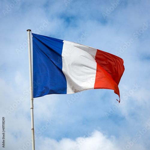French flag against blue cloudy sky.