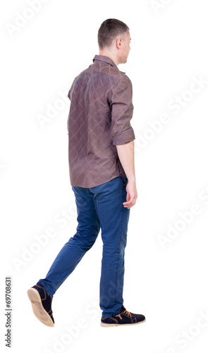 Back view of going handsome man in jeans and a shirt.