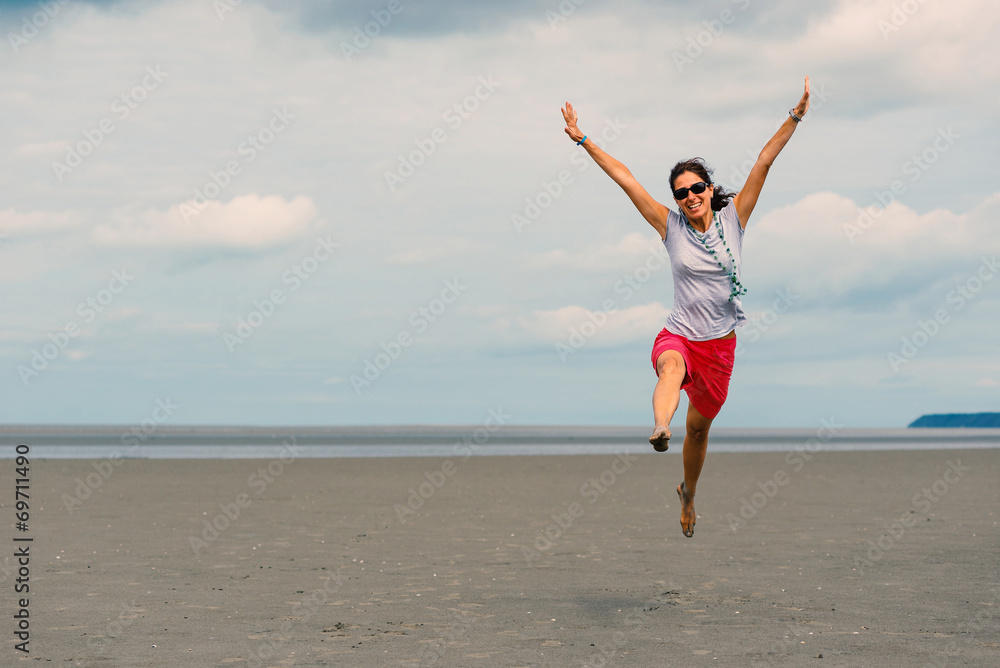 Happy woman jumping on the beach in front of Mont Saint Michel a Happy woman jumping on the beach in front of Mont Saint Michel a