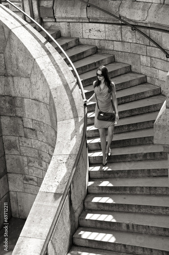 woman in sunglasses and dress walking down stairs