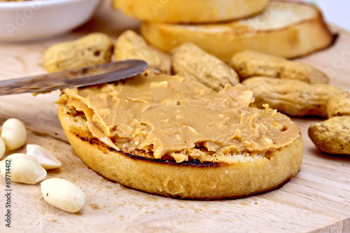 Sandwich with peanut butter and knife on board