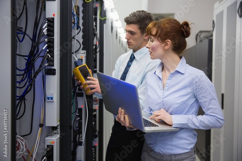 Team of technicians using digital cable analyser on servers