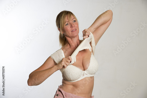 Obraz na plátne Woman getting dressed pulling shirt over her head