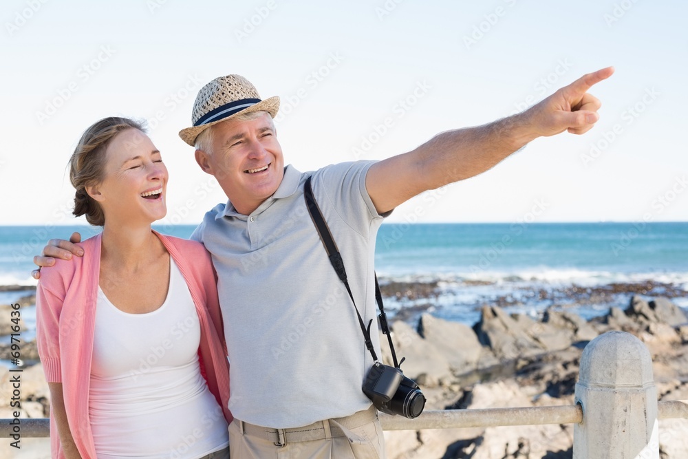 Happy casual couple looking at something by the coast