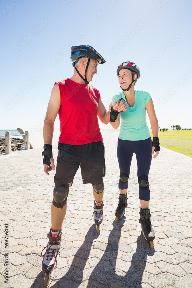 Fototapeta premium Fit mature couple rollerblading on the pier