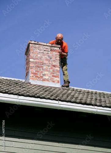 Man on a roof inspecting a chimney