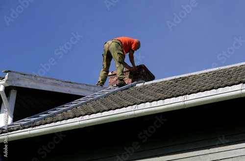 Man on a roof inspecting his chimney